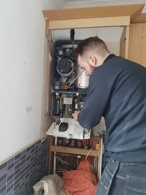 Engineer servicing boiler in kitchen cupboard