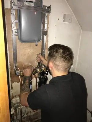 Engineer working on boiler installation in cupboard