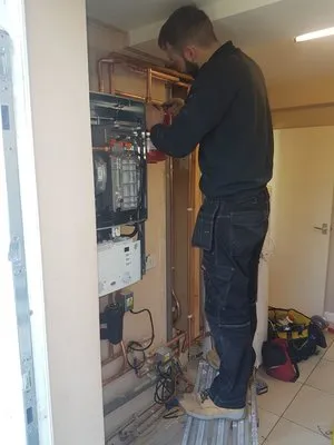 Engineer installing boiler system with exposed pipework