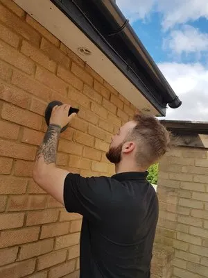 Engineer installing external flue pipe on brick wall