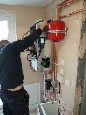 Engineer working on boiler controls and expansion vessel