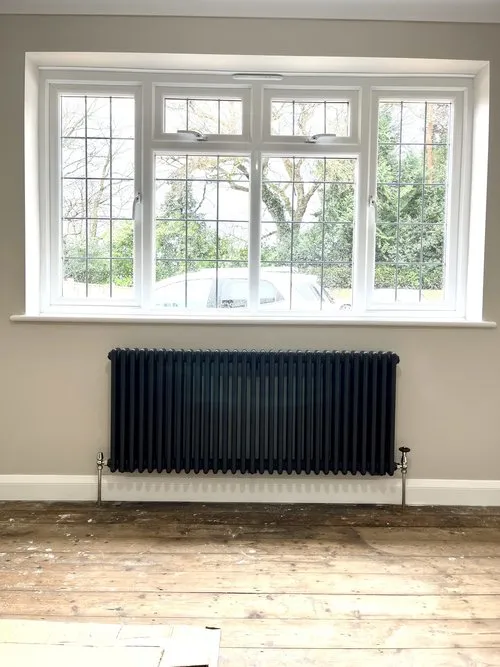 Traditional cast iron radiator installation under window